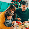 Papa, Mama, et petit garçon ouvrant un cadeau pour les fêtes de Noël